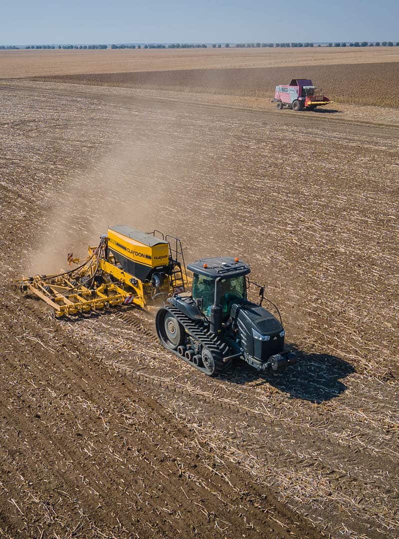 Ein Traktor, der mit einem Düngestreuer bestückt ist, bei der Arbeit auf dem Feld.