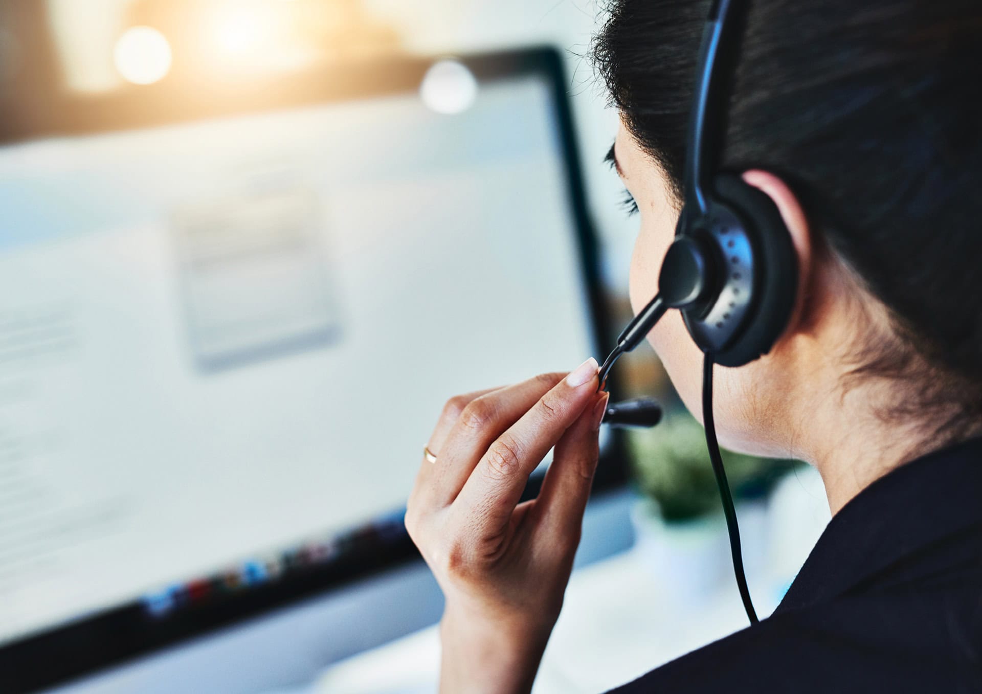 Eine Frau mit einem Headset beim Telefonieren vor einem Laptop