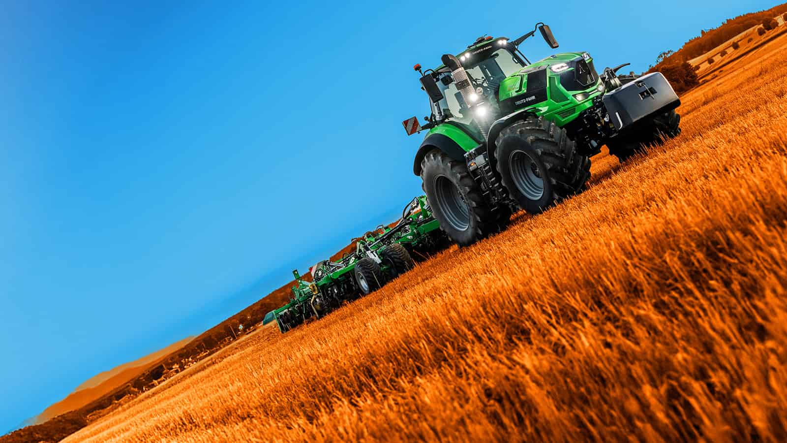 Traktor auf einem Getreidefeld, strahlend blauer Himmel