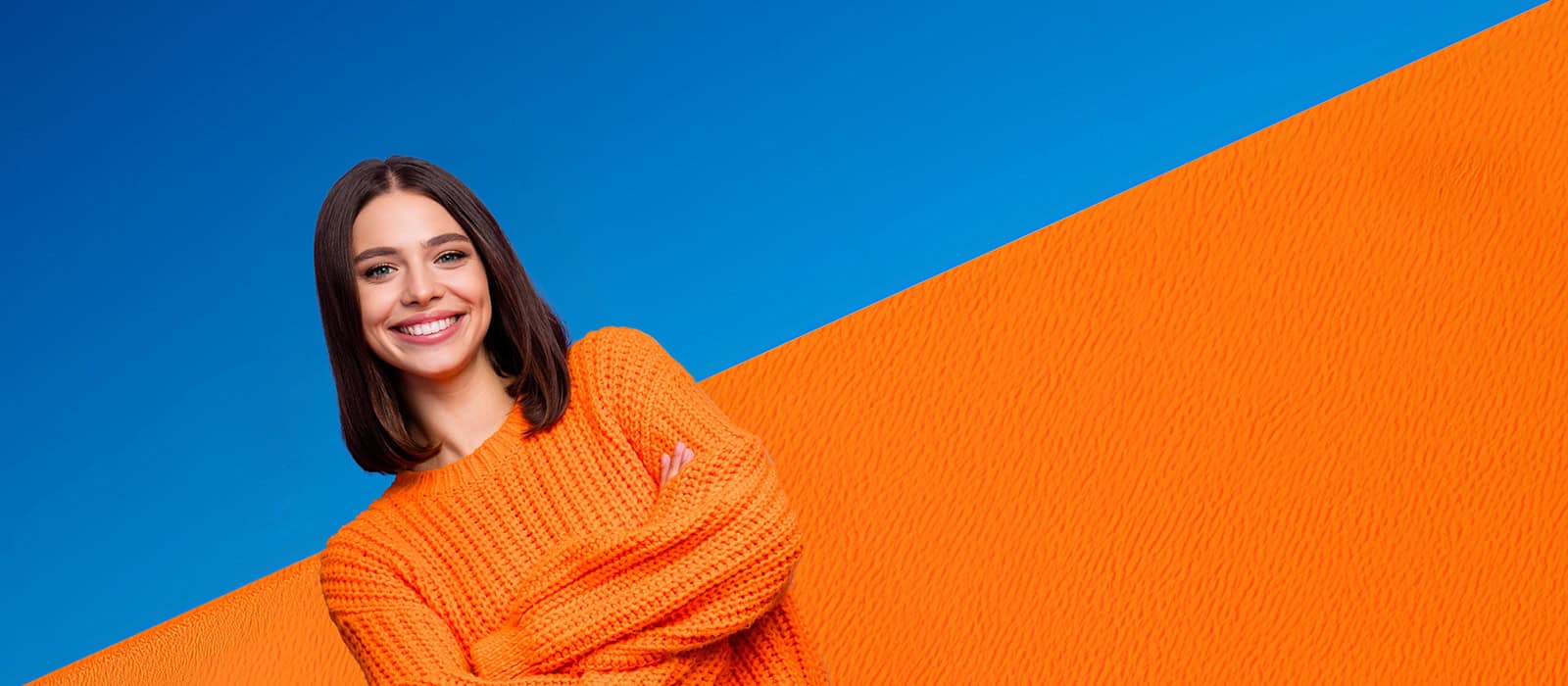 Eine lachende, sympathische, junge Frau mit orange/blauem Hintergrund im Fokus