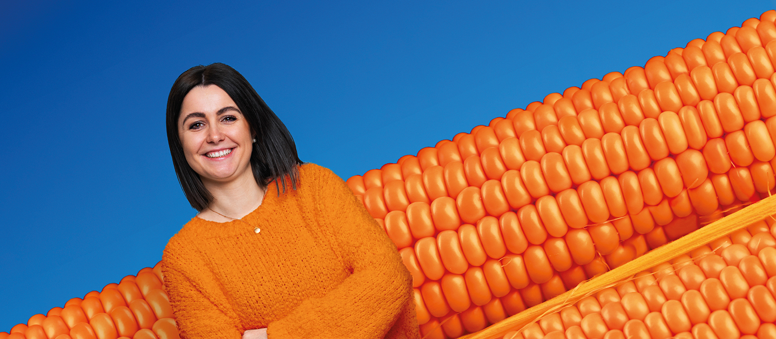 Eine lachende, sympathische, junge Kollegin mit orange/blauem Hintergrund im Fokus